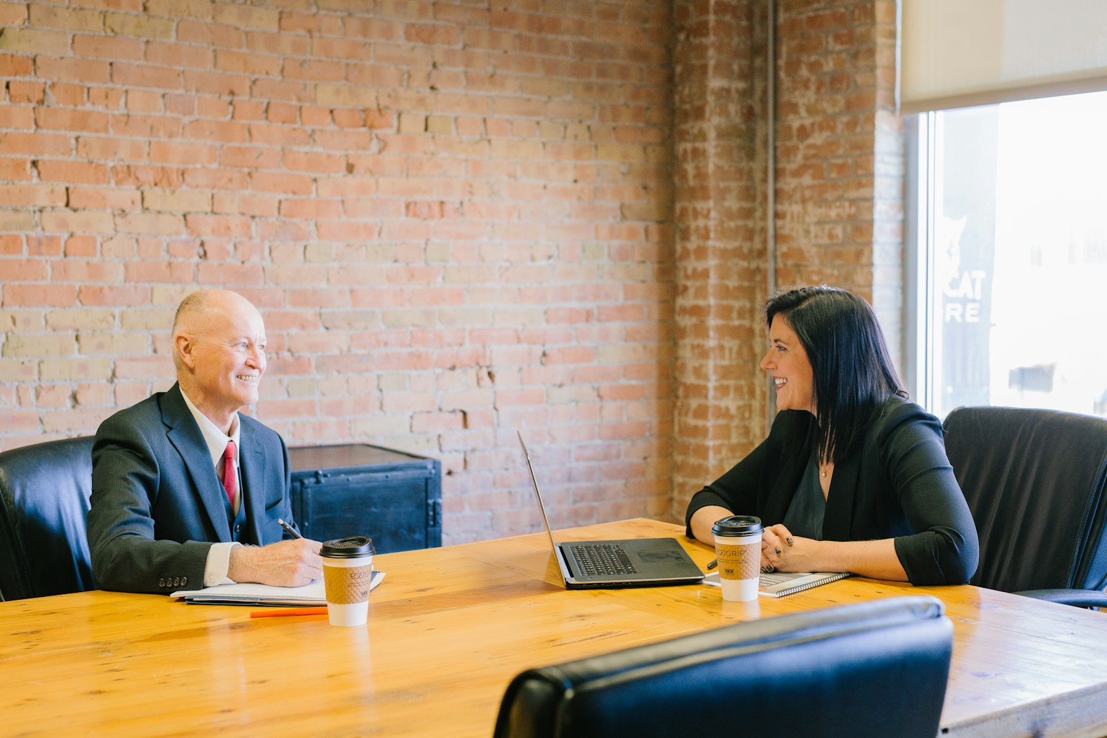 Two people in conversation across a desk in an office